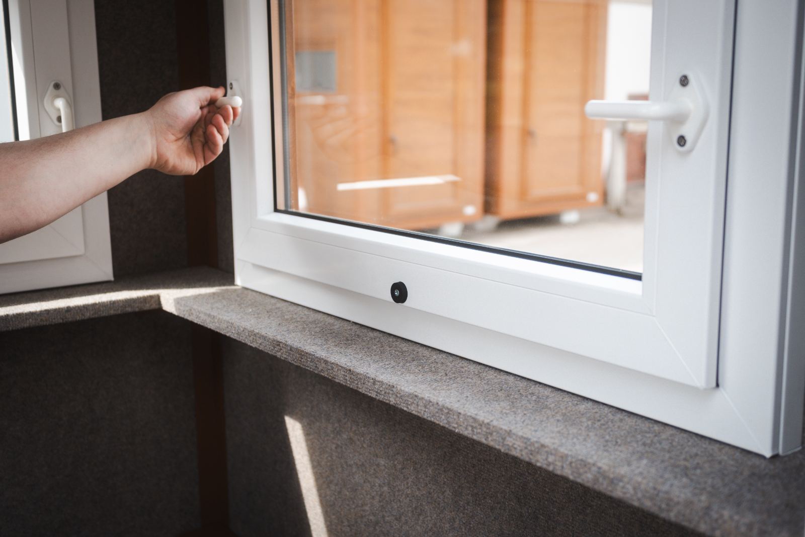 Hand öffnet ein Fenster im Innenraum